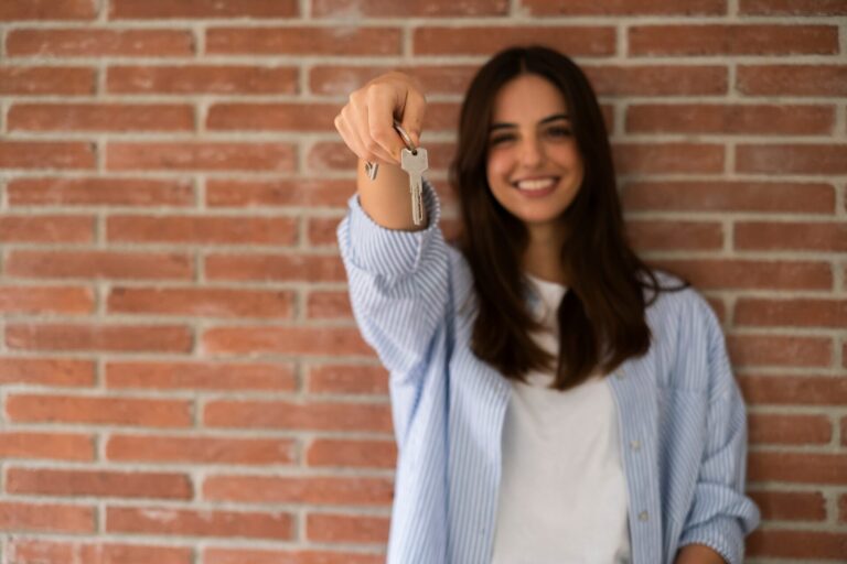 Happy,Woman,Holding,Keys,To,New,Home,,Looking,At,Camera